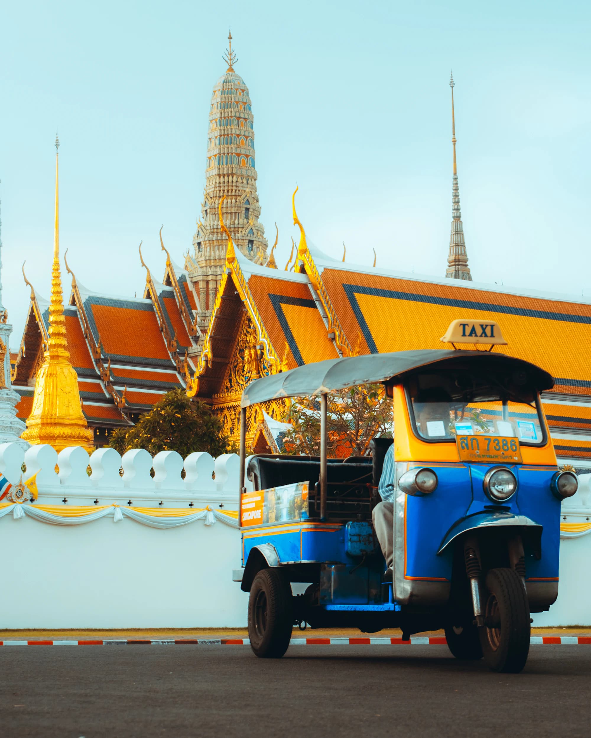 A tuk-tuk parked in front of golden temple roofs in Bangkok