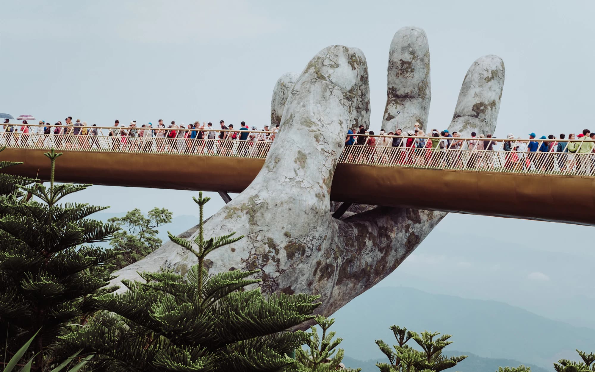 Visitors crossing the Golden Bridge, held up by giant stone hands, in the Ba Na Hills