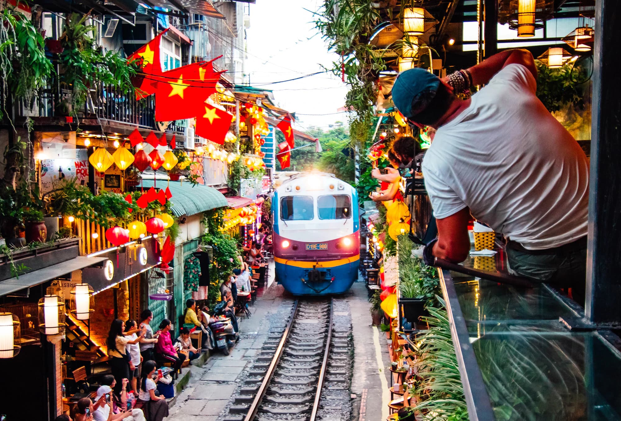 A train squeezing past cafés and onlookers on Hanoi's train street