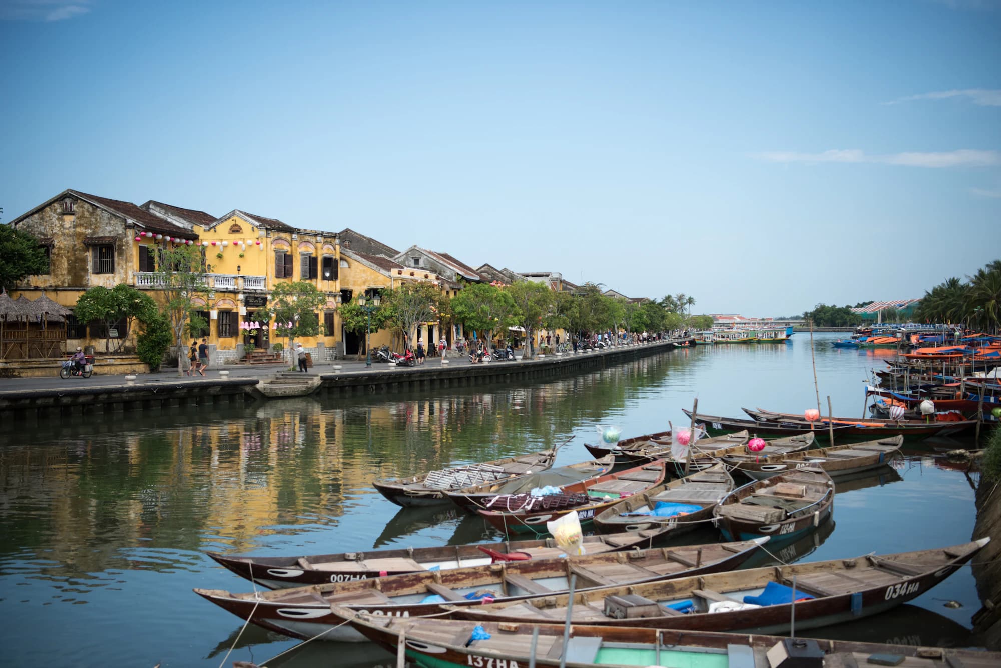 Wooden boats moored in front of Hoi An's yellow riverside houses