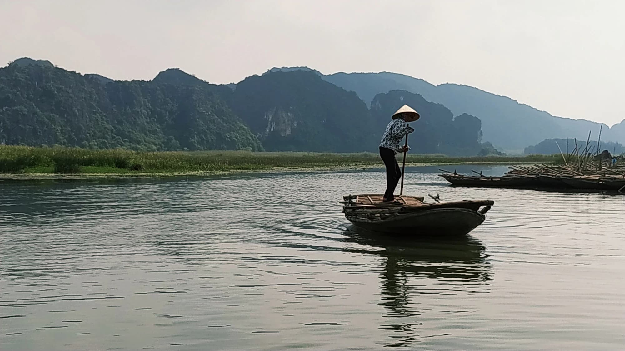 A rower in a conical hat on the river at Ninh Binh