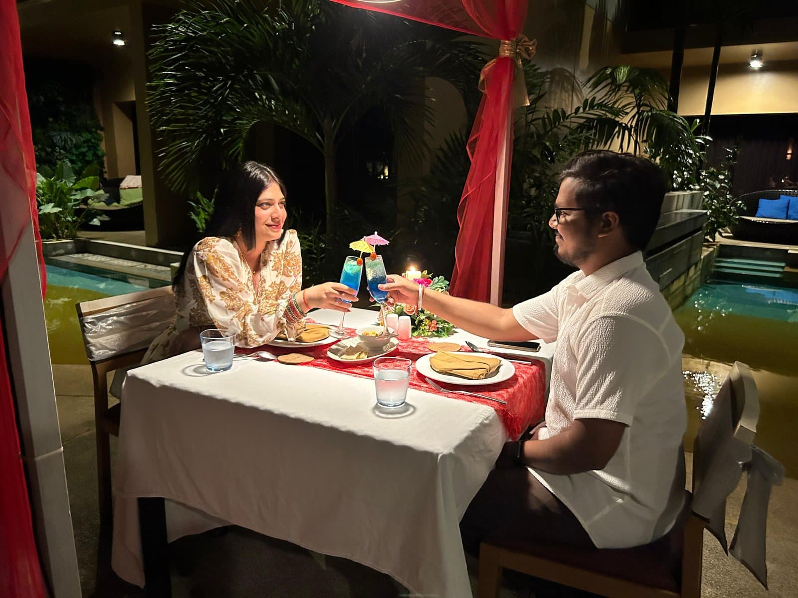 A couple at a candlelit dinner by the pool, Thailand