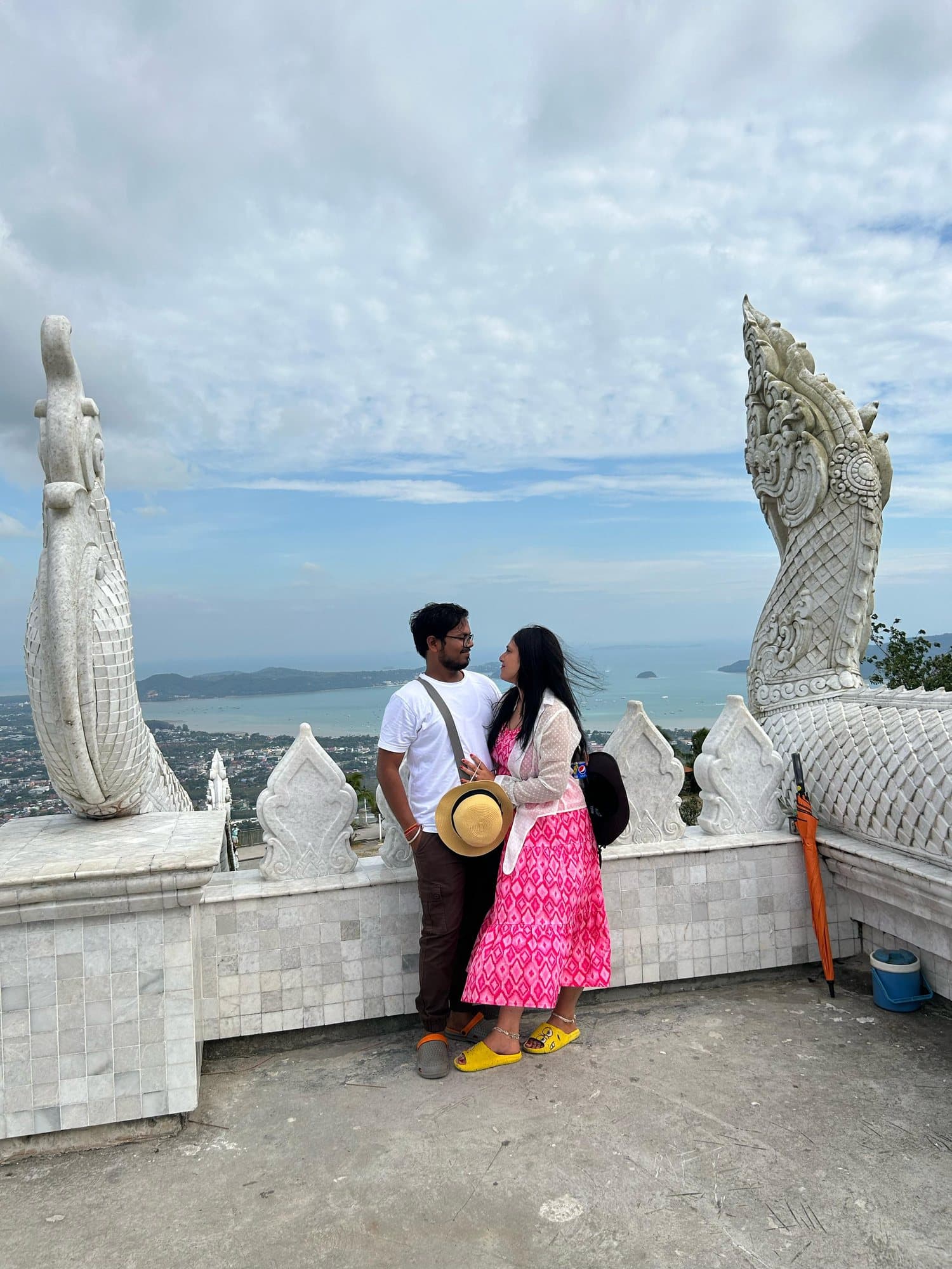 A couple by a naga statue at a sea viewpoint, Thailand