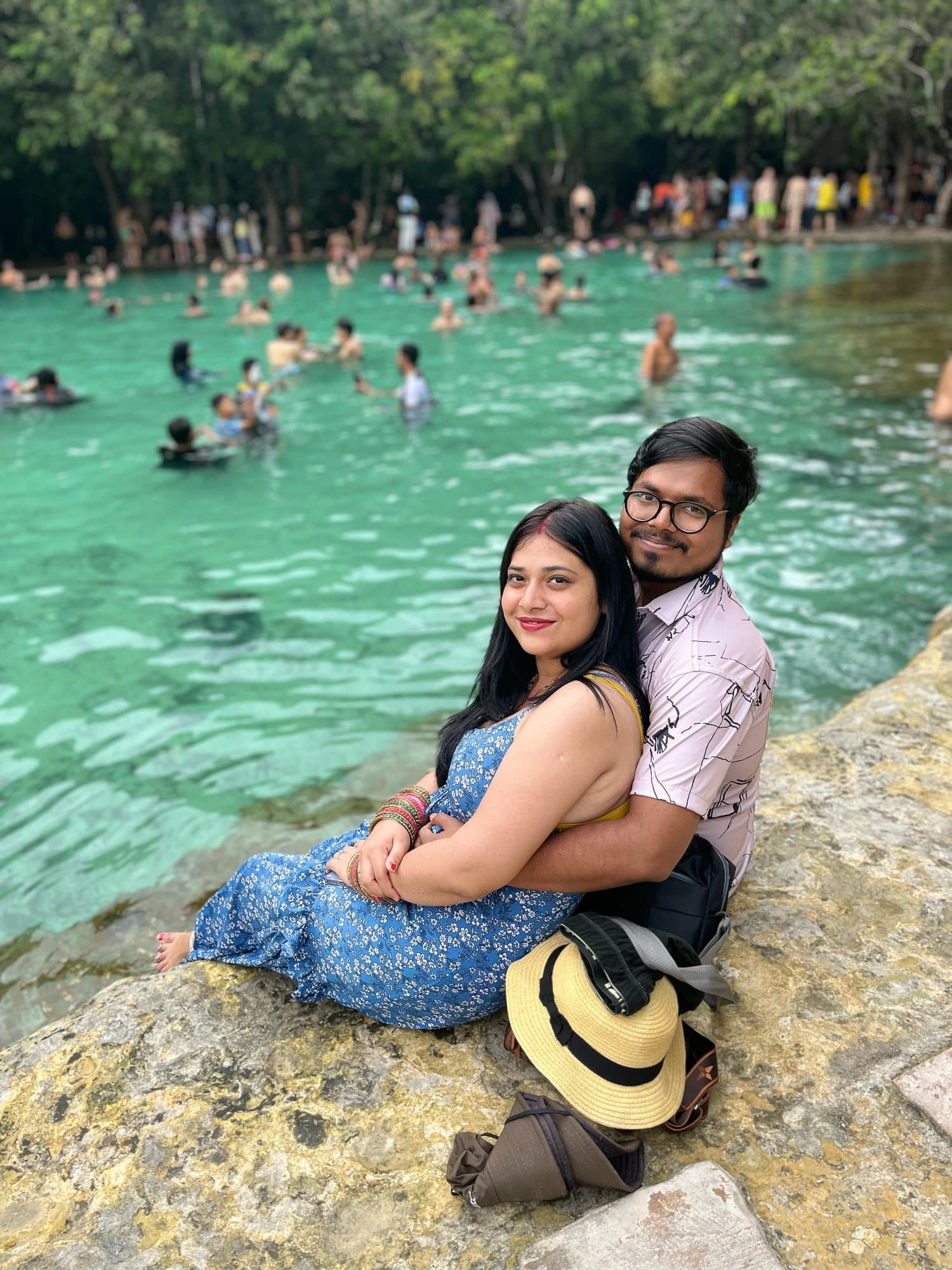 A couple on the rocks by a turquoise pool, Thailand